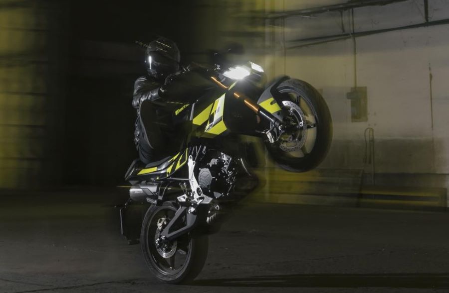 Un piloto hace caballito sobre una moto Fantic Stealth 500 ver con las luces encendidas
