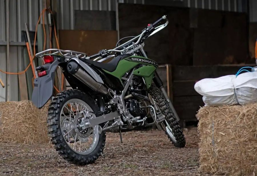 Una moto Kawasaki Stockman estacionada a las puertas de un granero