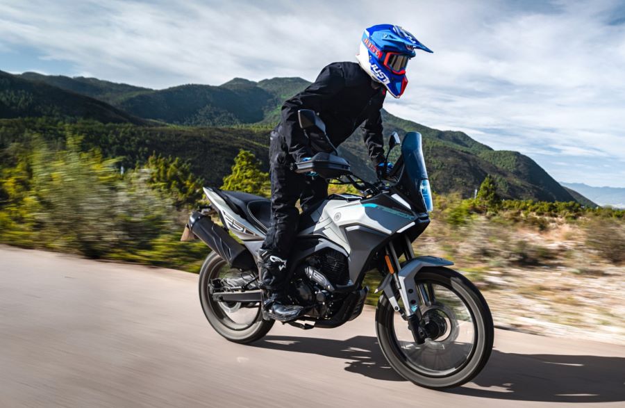 Un piloto se para sobre los pedalines de una moto Morbidelli T250X en una ruta de montaña