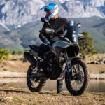 Un piloto mira hacia atrás sentado sobre una moto Morbidelli T250X con un fondo montañoso