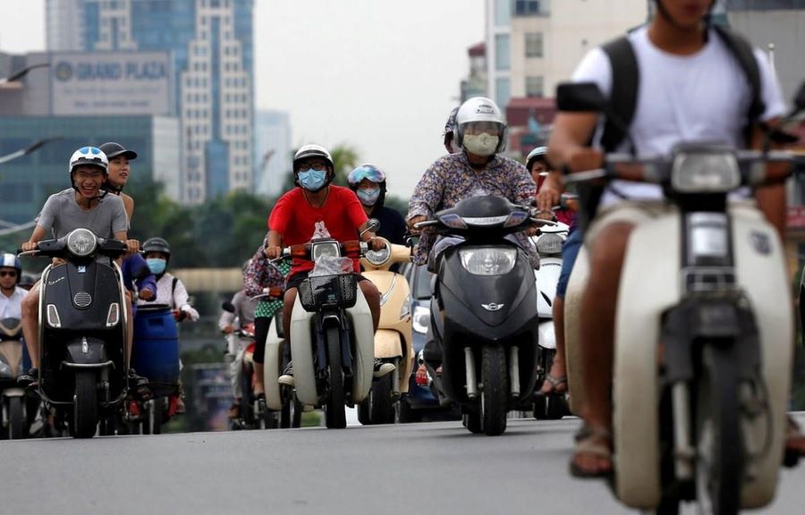 Motociclistas que portan barbijos avanzan en el tránsito de Hanoi, Vietnam