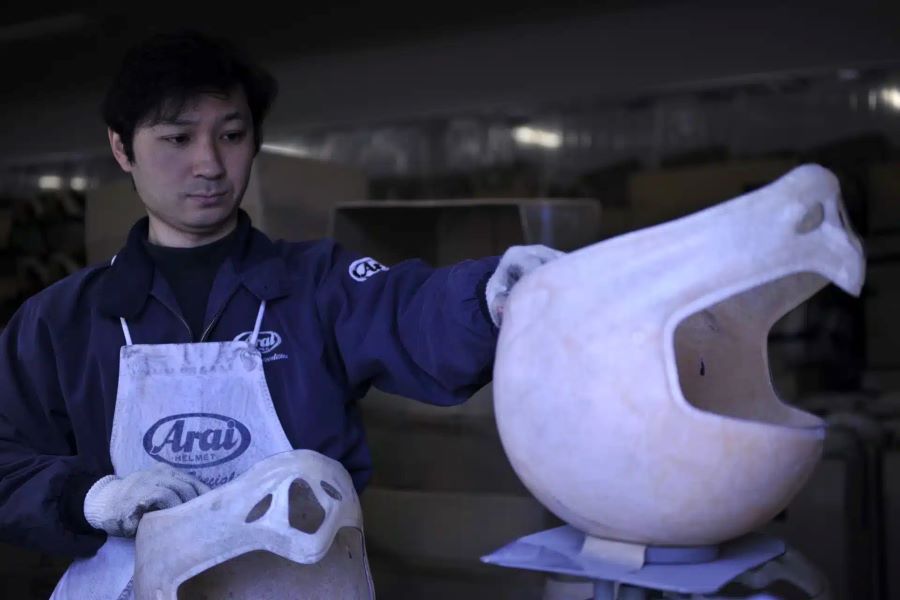 Un operario manipula un casco en proceso de fabricación en la sala de producción de Arai