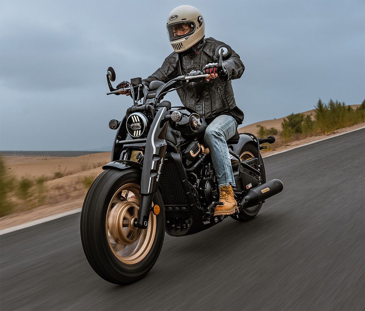 Una custom Cyclone RA600 negra con llantas doradas se desplaza por una carretera