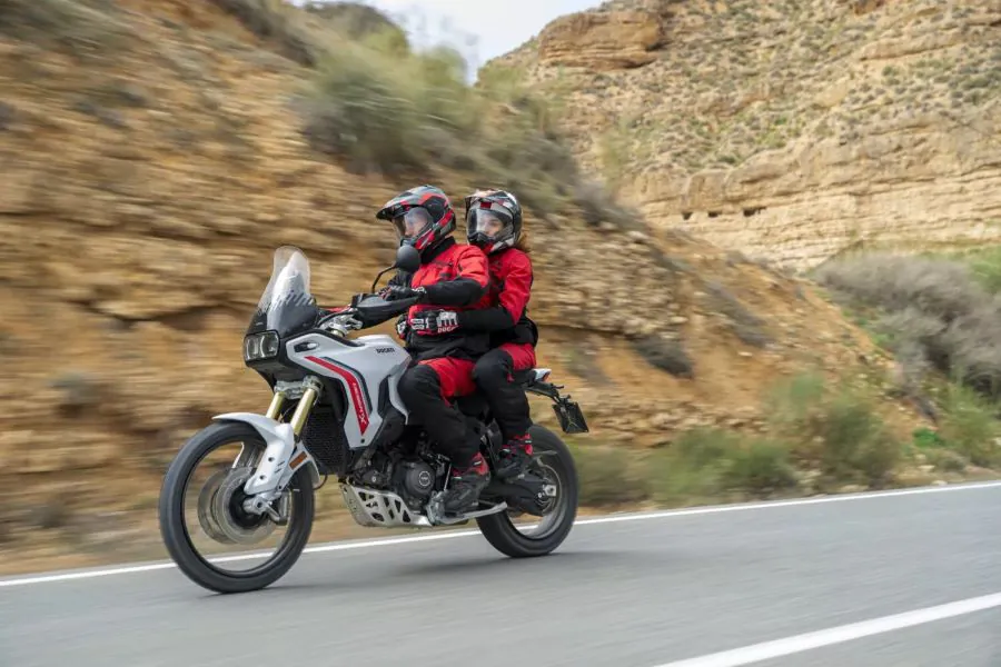 una pareja de moteros se desplazan sobre una moto Ducati DesertX 2026 blanca
