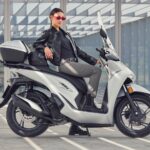 Honda SH125i: 25 años del scooter líder en Europa Una bella modelo juvenil posa sobre un scooter Honda SH125i 2026 color claro