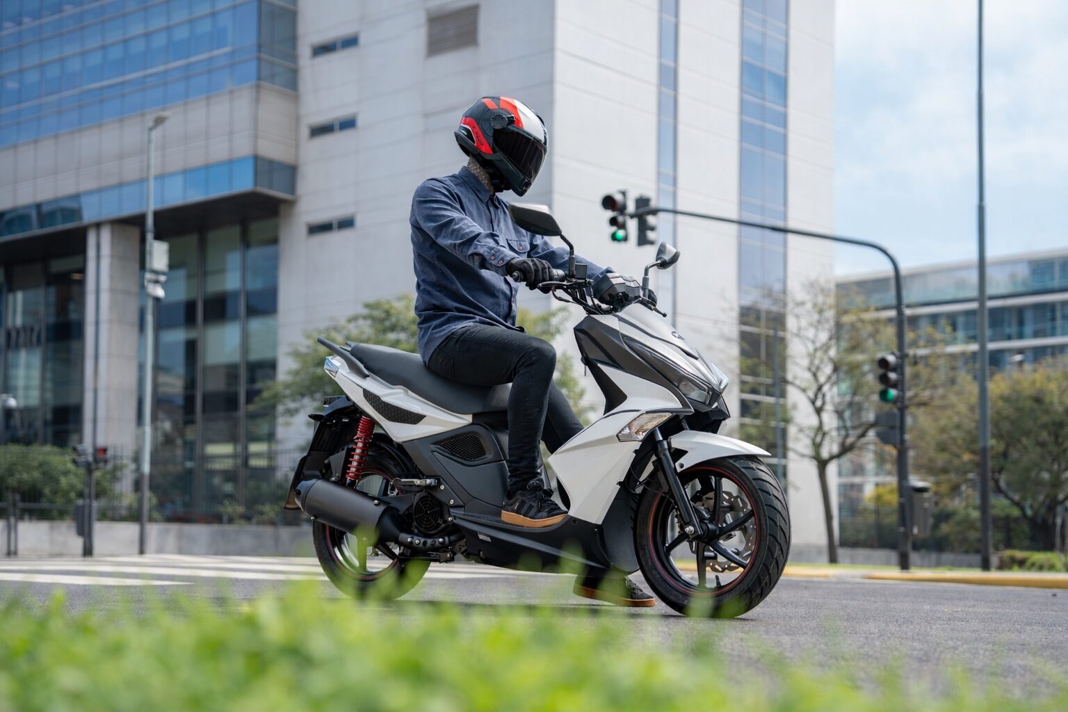  Un usuario, pie en tierras, aguarda el verde del semáforo para seguir con su scooter Kymco Super 8 150 blanco