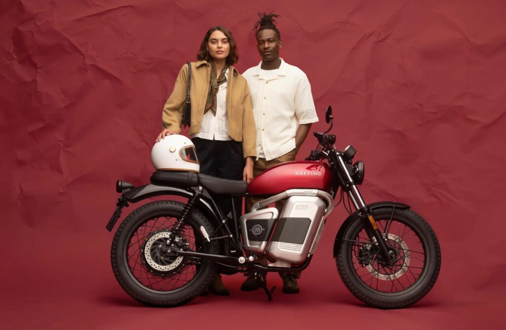 Una pareja de motociclistas posa detrás de una moto eléctrica Maeving RM2 roja