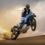 Las mejores motos adventure 450 del mundo en 2026 Una moto trail de 450 cc se impulsa en la arena con la rueda delantera levantada