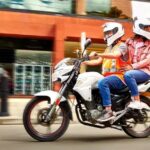 Un motociclista se desplaza con una pasajera que gira su cabeza hacia atrás