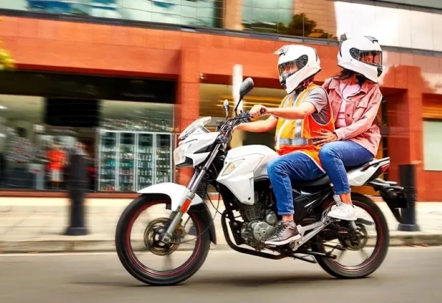 Un motociclista se desplaza con una pasajera que gira su cabeza hacia atrás