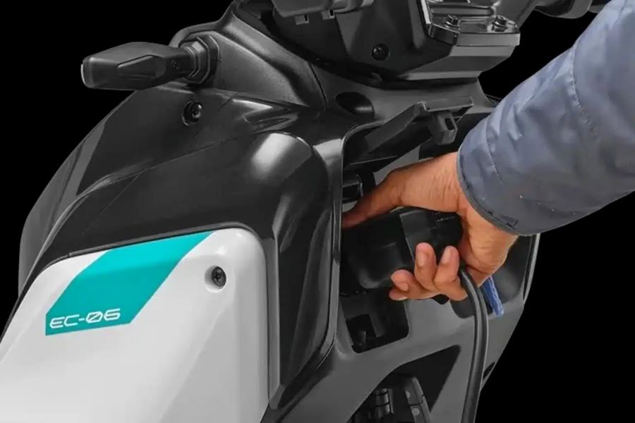 Una mano enchufa el cargador a un scooter Yamaha EC-06