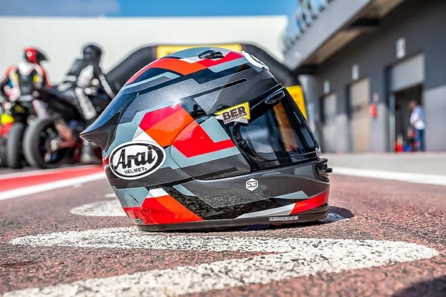 Un casco deportivo de la marca Arai ubicado sobre el asfalto de un circuito