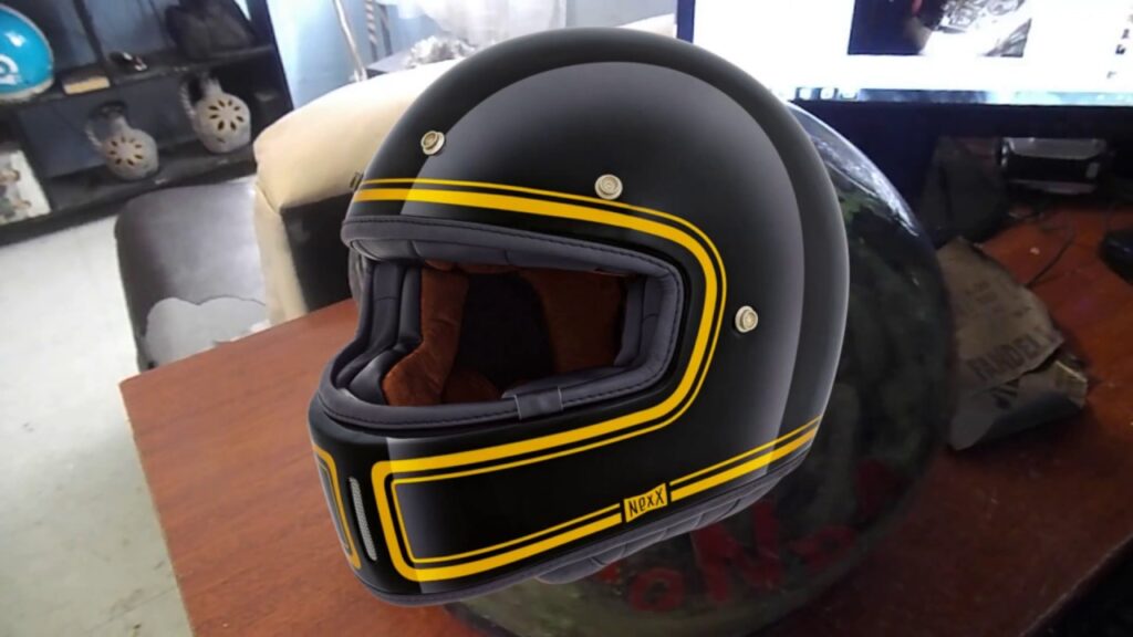 Un casco de moto negro intervenido con una línea amarilla pintada que recorre el exterior de visera y la base del mismo.