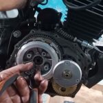 Una persona trabaja con una herramienta en un motor de moto