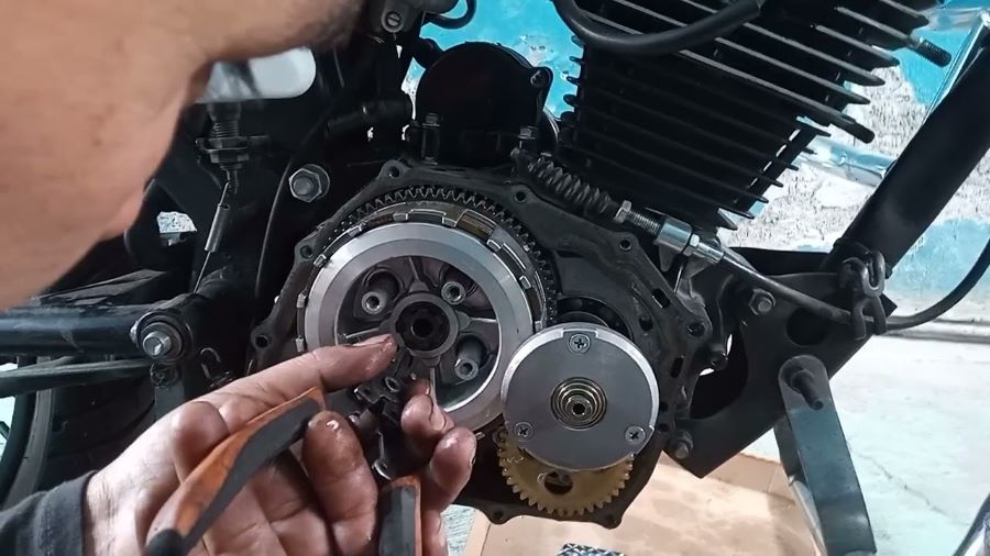 Una persona trabaja con una herramienta en un motor de moto