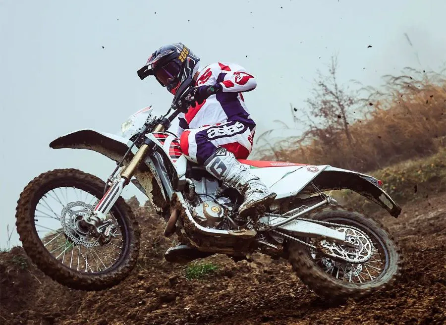 Un piloto derrapa en el barro con una moto Bimota BX450 blanca