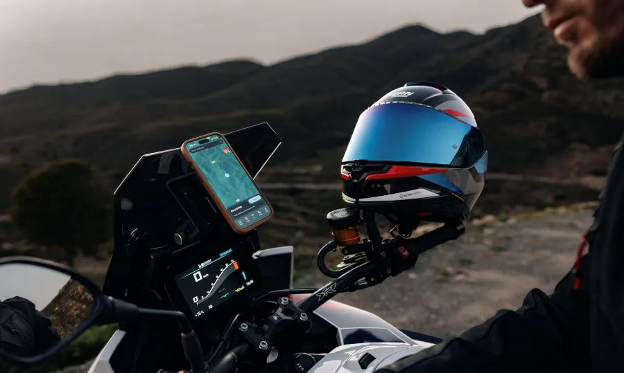 Un motociclista programa su navegador al casco Nolan X-904 Ultra Carbon apoyado en el espejo retrovisor de la moto