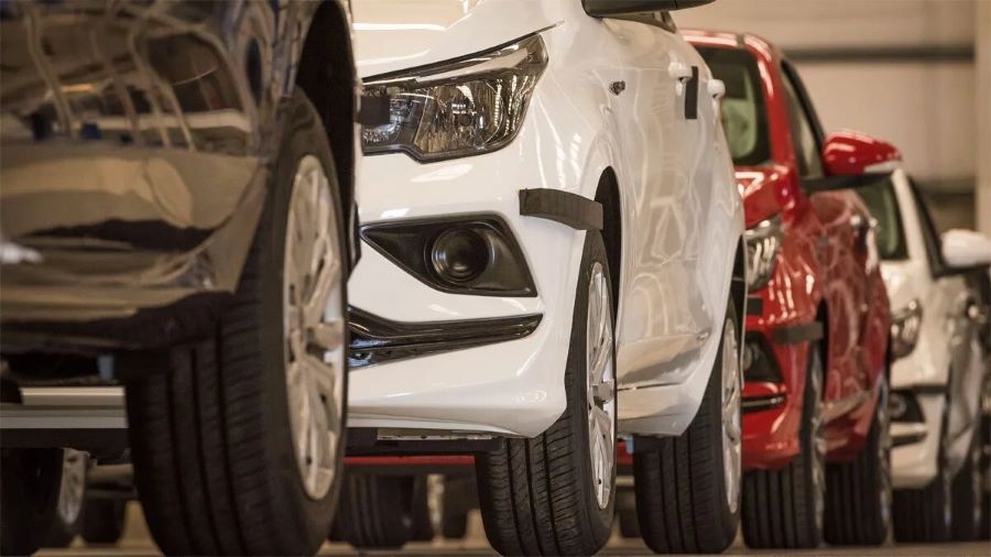 Vista parcial de cuatro autos en fila dentro de un salón