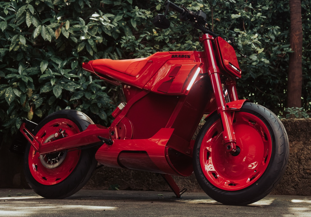 Una moto Brabus Urban E roja posa delante de una pared de hojas verdes