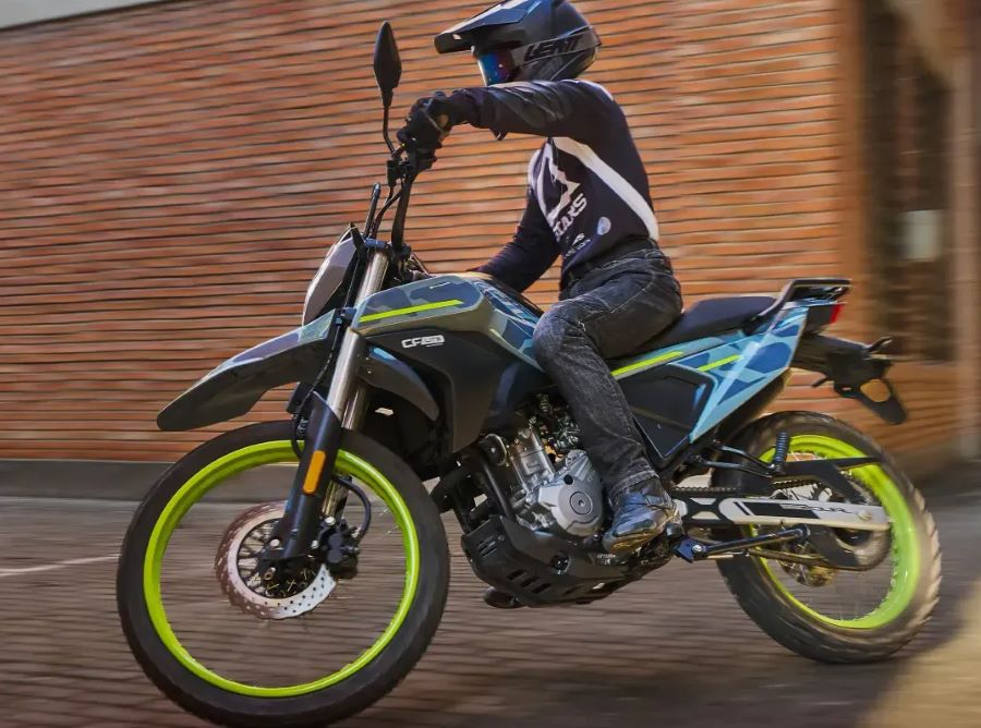 Un piloto dobla una esquina con su moto CFLITE Dual 250 gris y verde flúor