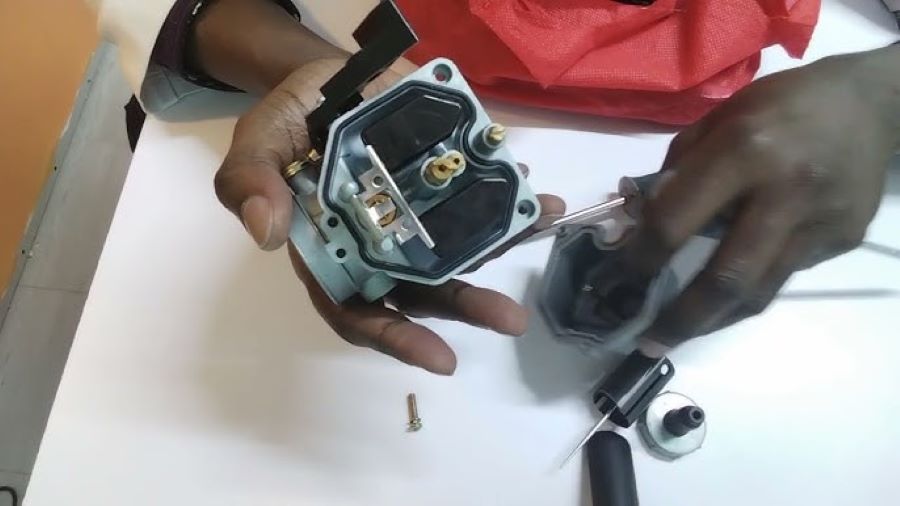 Manos de un técnico desarman un carburador PZ27 para moto