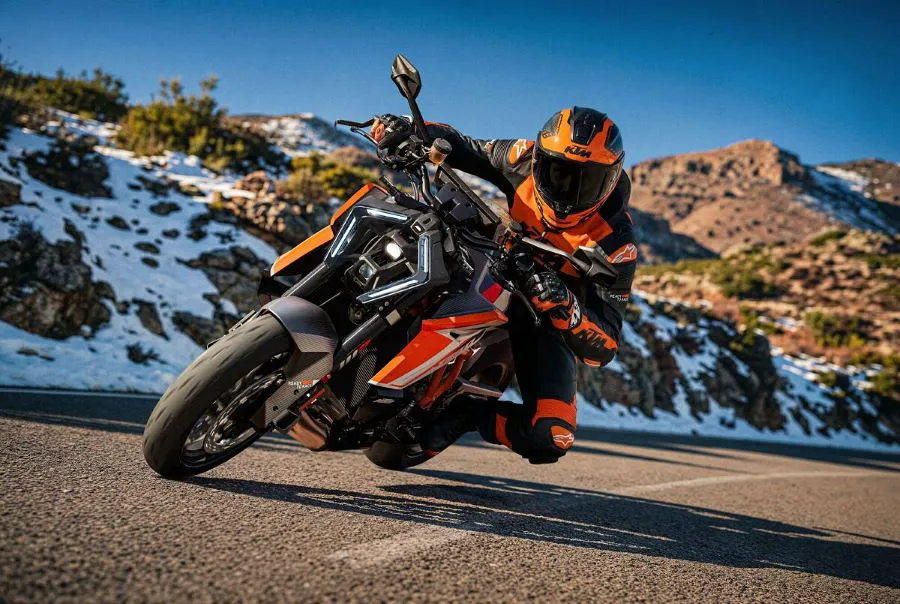 Una moto KTM 1390 Super Duke RR 2026 gira a la izquierda en una ruta bordeada por nieve