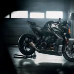 Una moto KTM 1390 Super Duke RR Track posa sobre su caballete en un ambiente apenas iluminado por tres ventanitas