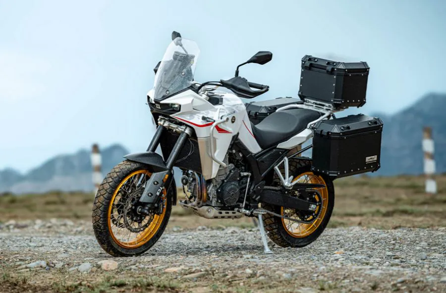 una Moto Kove 800X GT blanca descansa sobre la grava