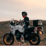 Un piloto con casco está sentado sobre una Moto Kove 800X GT en medio de la montaña