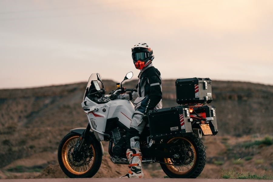 Un piloto con casco está sentado sobre una Moto Kove 800X GT en medio de la montaña