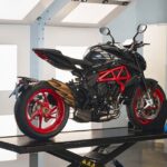 Brutale 800 Nero Carbonio: oscura, elegante y más provocadora vista lateral derecha de una moto MV Agusta Brutale 800 Nero Carbonio sobre una plataforma y con ventanas luminosas de fondo