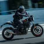 Un piloto, que circula a gran velocidad sobre una Royal Enfield Gerrilla 450 Apex, gira la cabeza hacia atrás