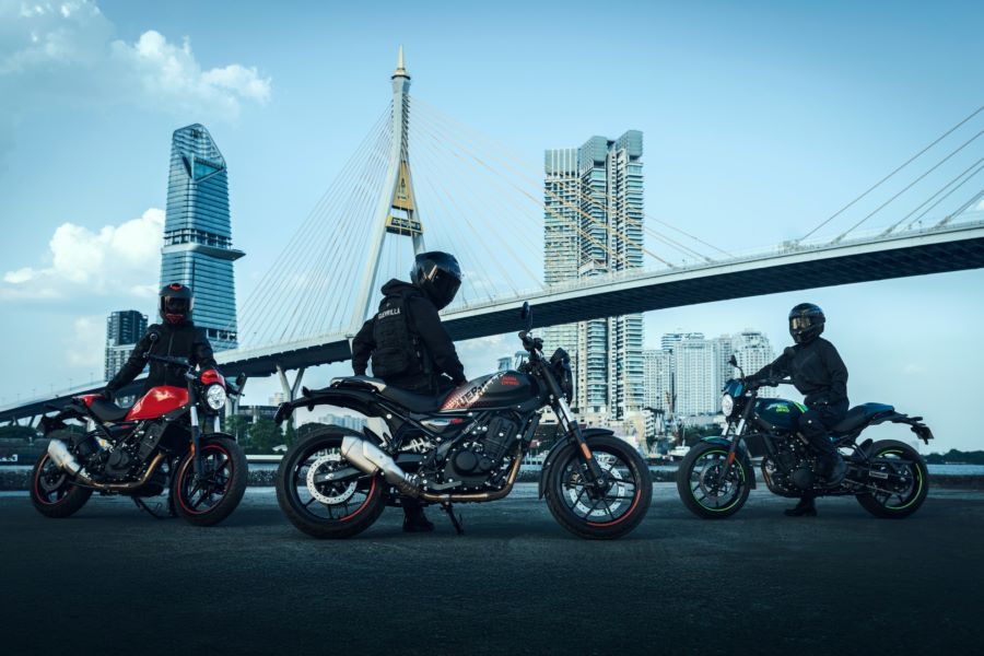 Tres motociclistas posan con sendas Royal Enfield Gerrilla 450 Apex con un puente y una ciudad futurista de fondo