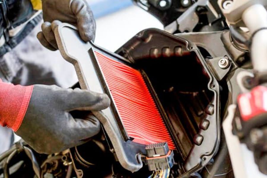 una mano de un mecánico retira filtro de moto