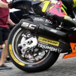 Vista parcial de un mecánico empujando una moto de Moto2