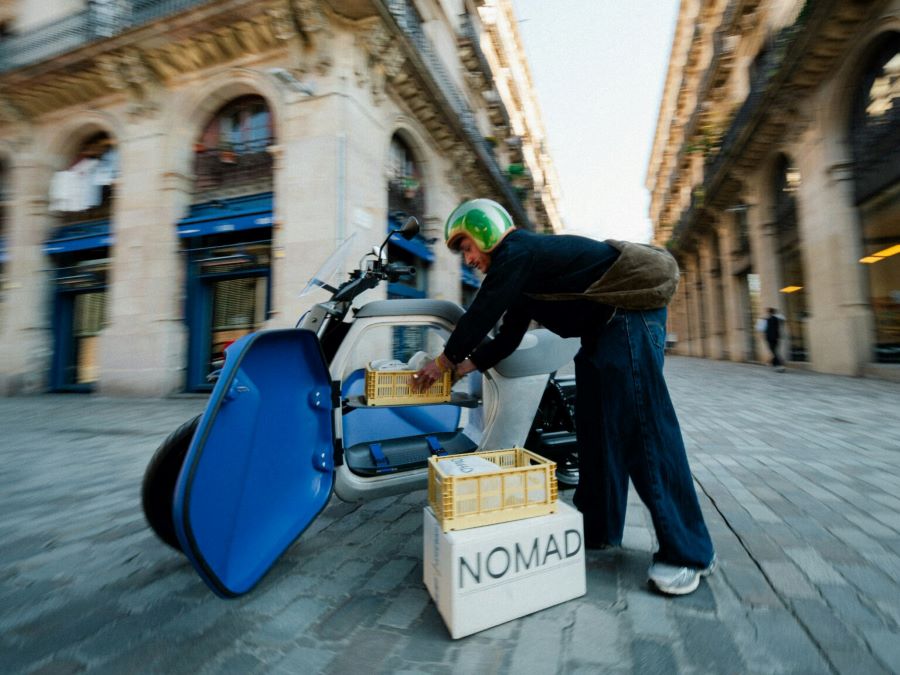 Un empleado carga cajas al baúl de una moto eléctrica ANY LUV 1