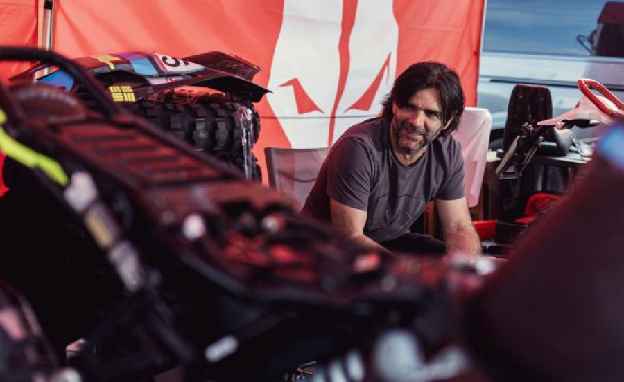 Charly Sinewan ¿Por qué es una referencia de viajes en moto? El motoviajero charly sinewan posa detrás de una moto