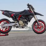 vista lateral derecha de una Moto Ducati Supermotard negra con llantas rojas