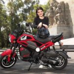 Una adolescente mira sonriente apoyada en su moto Italika BIT 150 roja