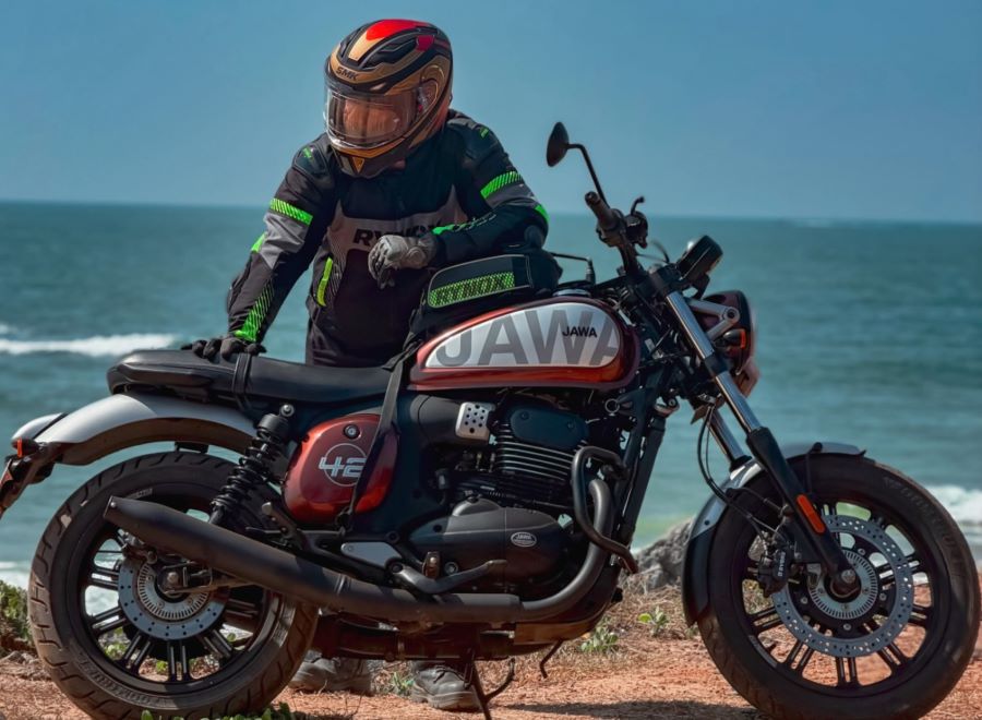 Un usuario de apoya sobre su moto Jawa 42FJ para observar el paisaje marino