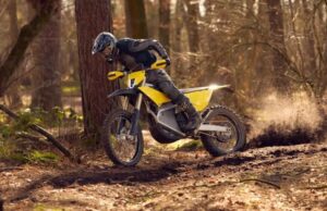 Un piloto, parado sobre las estriberas, maniobra una moto Radian EXR en un sendero boscoso.