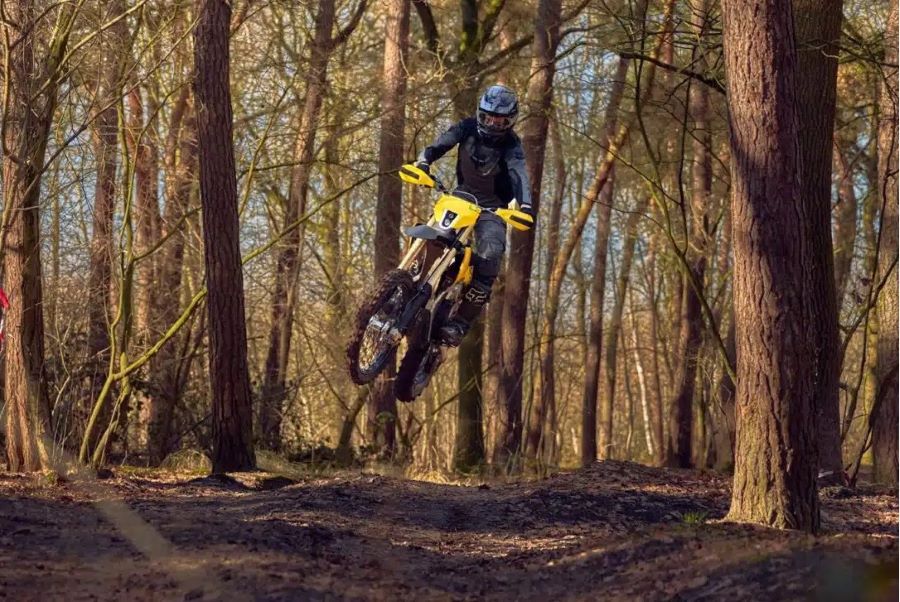 En medio de un bosque, un piloto salta sobre su moto eléctrica Radian EXR
