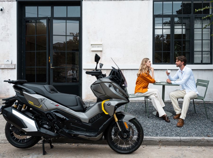 Una pareja disfrurta de un café en la vereda al lado de su scooter VOGE SR450X