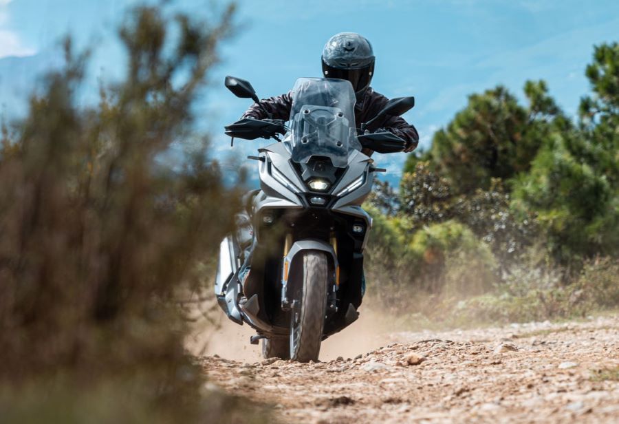 Un scooter VOGE SR450X viene de frente por un sendero de tierra con las luces encendidas