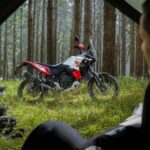 Un silueta de un hombre mira a distancia su Yamaha Ténéré World Raid 2026 parada en un bosque verde