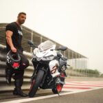 La Aprilia RS 457 empieza donde otras deportivas terminan Un piloto, casco en mano, se apoya en el guardrail al lado de su moto Aprilia RS 457 blanca