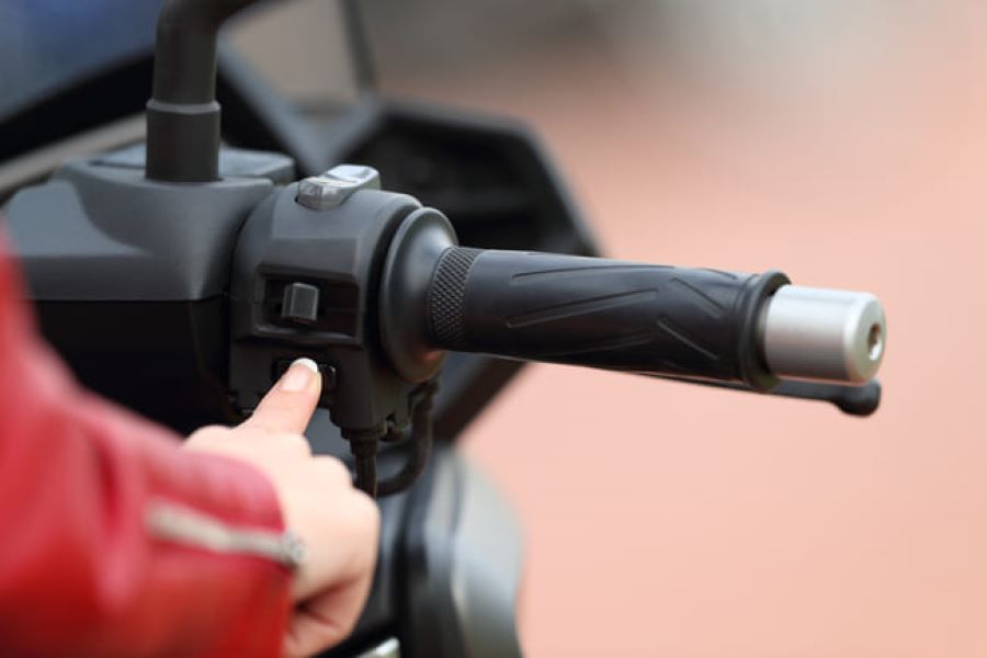 una mano de mujer acciona el arranque electrónico de un moto