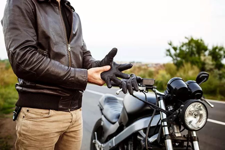 Un hombre se quita los guantes a un costado de su moto