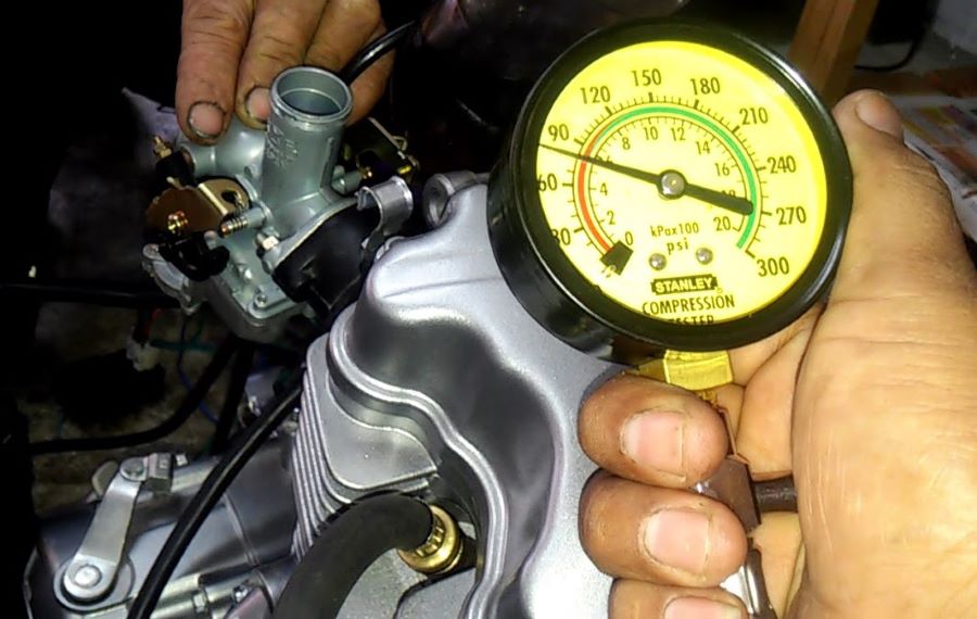 Una mano muestra un medidor de compresión para motor de moto