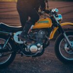 Un motociclista intenta arrancar su moto amarilla con una patada